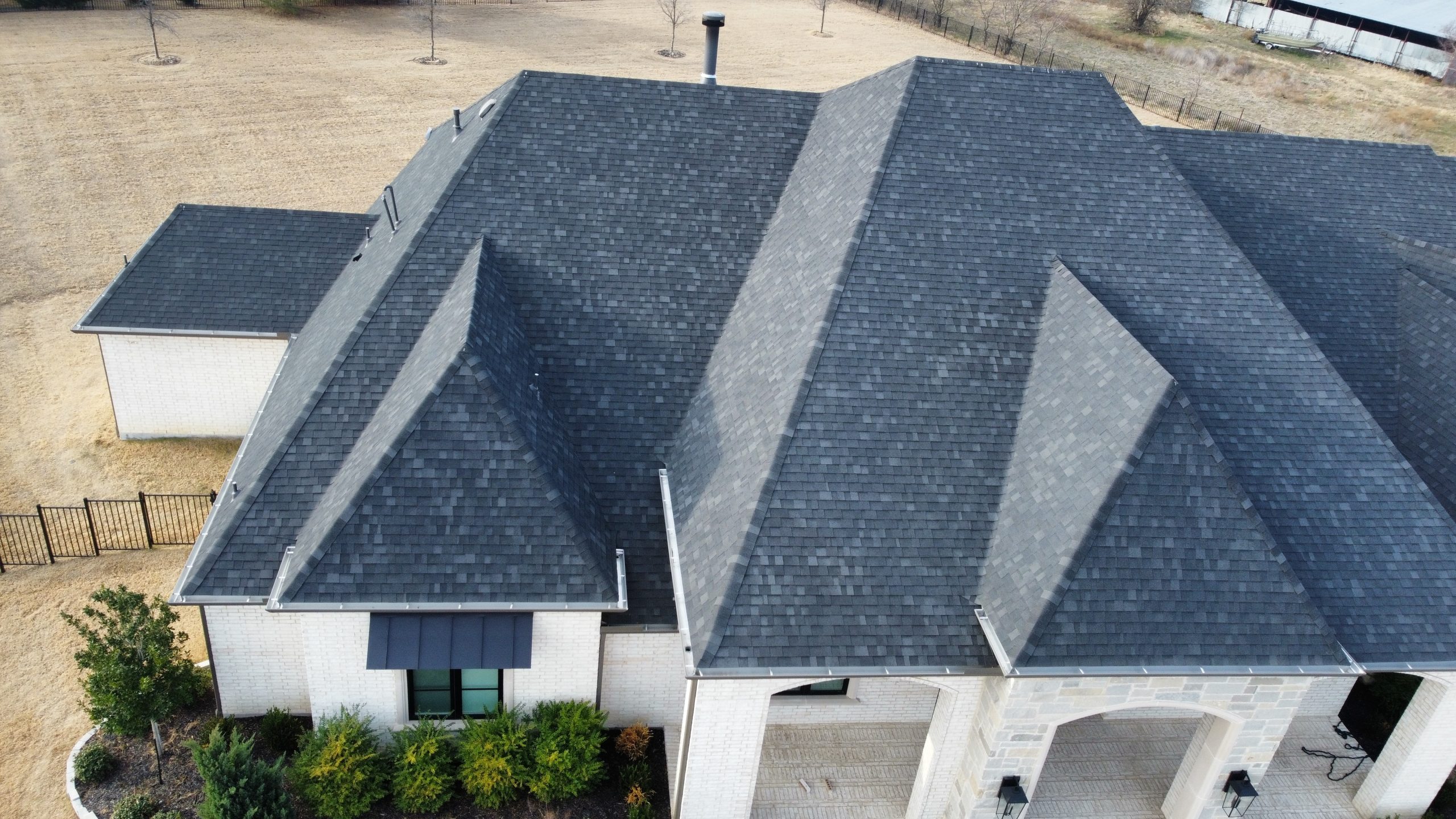 Aerial view of completed asphalt shingle roof replacement in Aubrey TX after storm damage